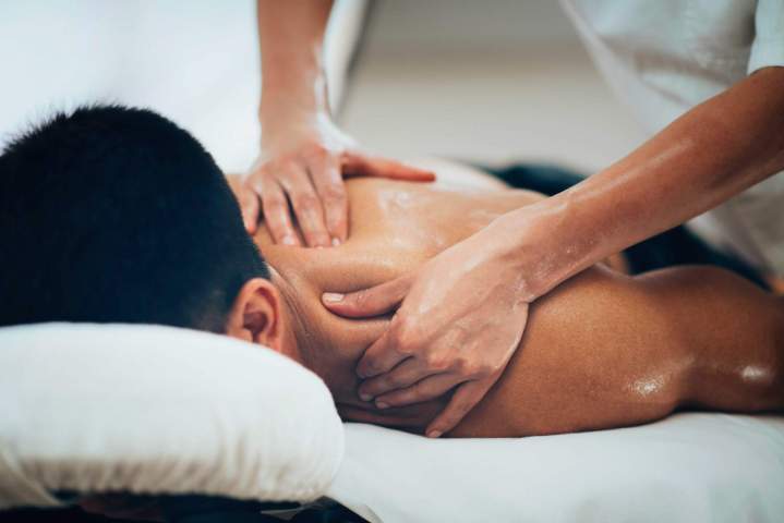 Gros plan sur un dos recevant un massage relaxant, les mains de la praticienne travaillant les muscles pour libérer les tensions.